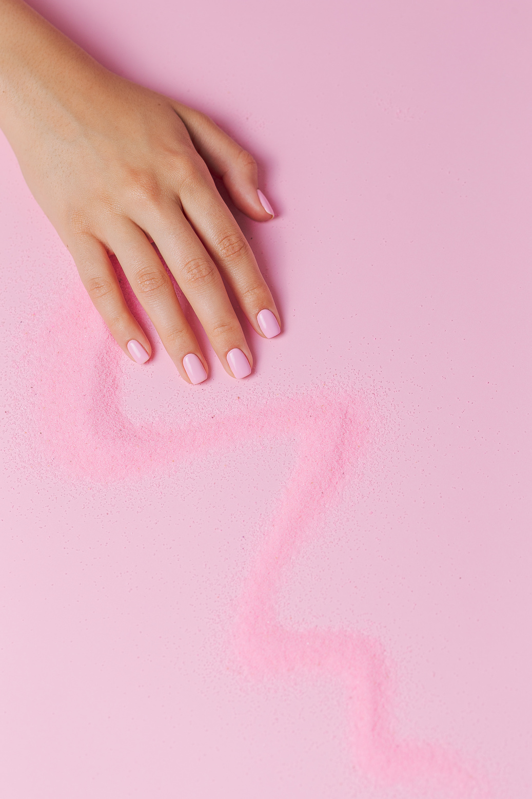 Hand on a Surface with a Trail of Pink Powder